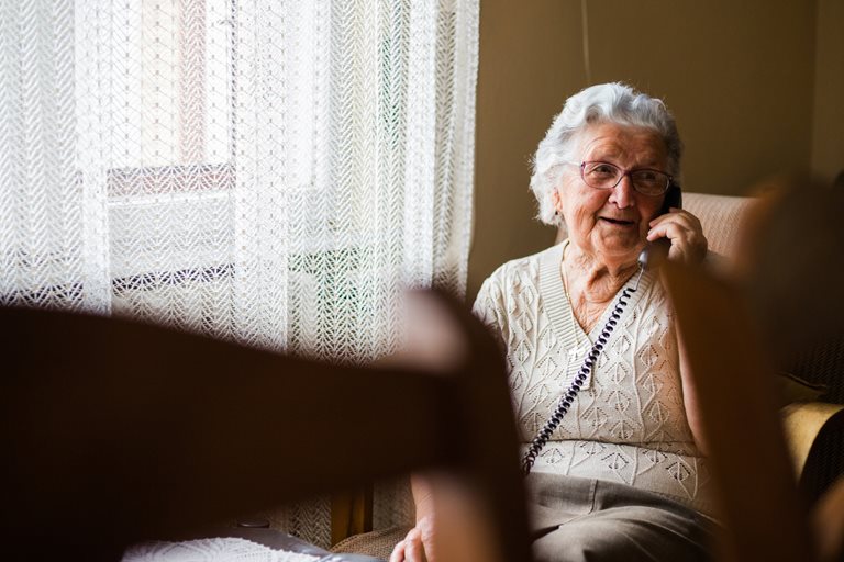 An elderly woman speaks on the phone.